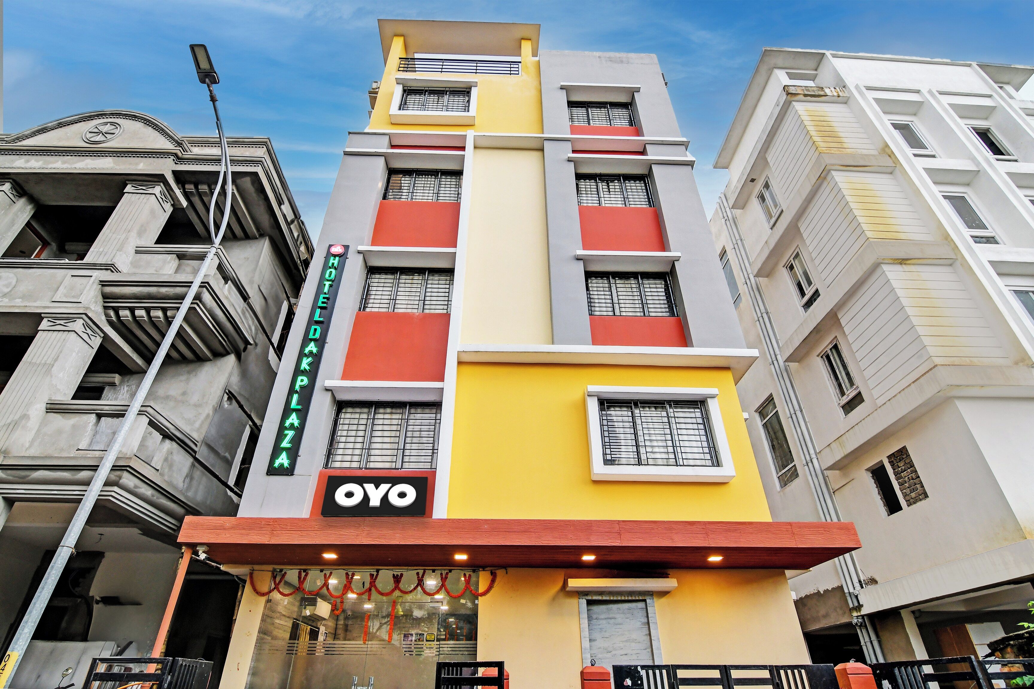 Un hotel de varios pisos con un cartel llamativo que dice 'HOTEL', un logotipo 'YOYO' y un cartel que dice 'HOTEL PLAZA'.