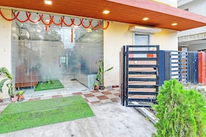 A building entrance with a glass door, a checkered floor, and a small green lawn area. - HotelO Dak Plaza Balaka Bus Terminus (Kolkata)