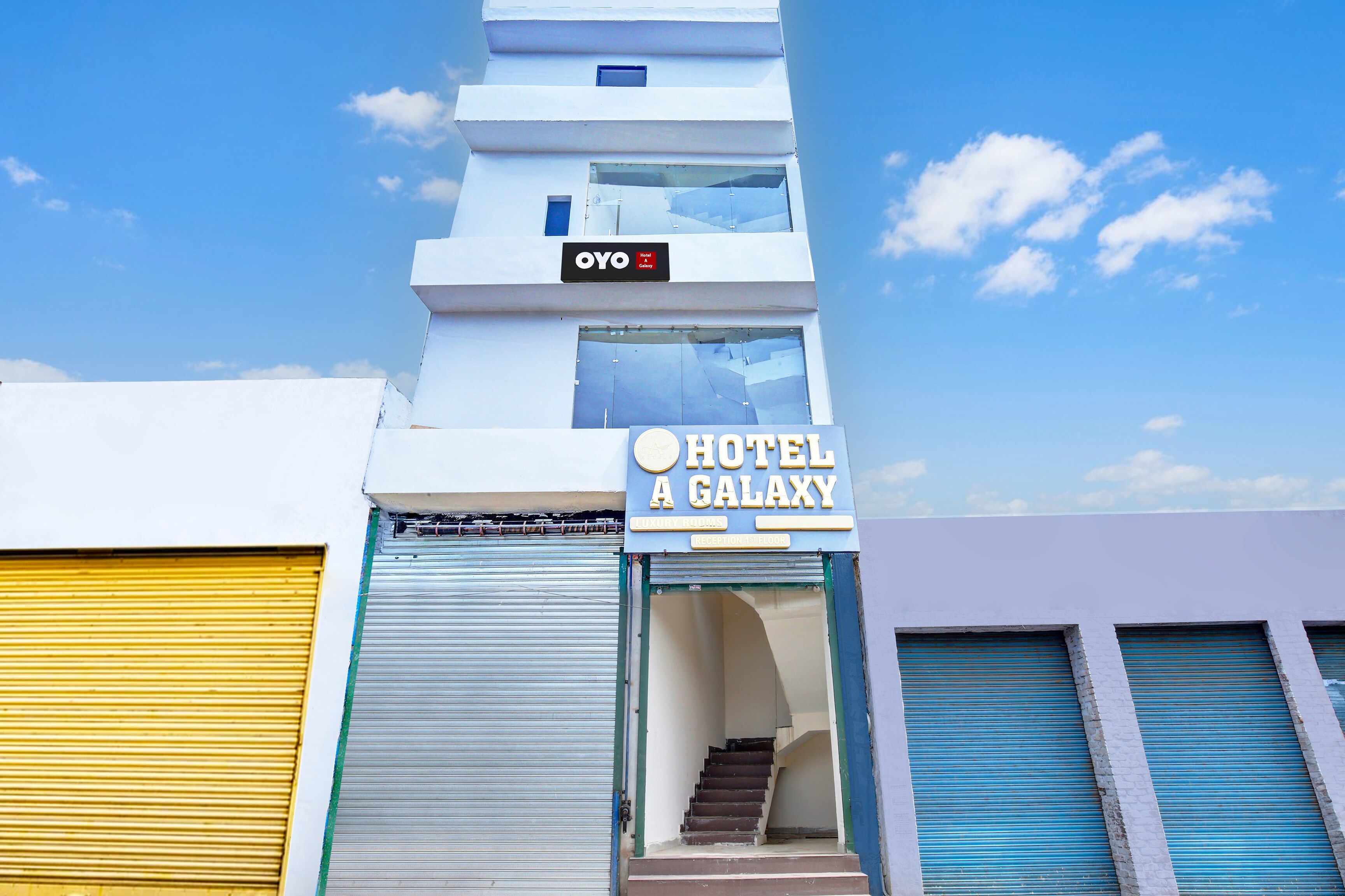 Un hôtel avec une enseigne indiquant « HÔTEL A GALAXY » et un escalier menant à la réception, située au premier étage.