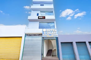 Um hotel com uma placa indicando 'HOTEL A GALAXY' e uma escadaria que leva à recepção no primeiro andar.