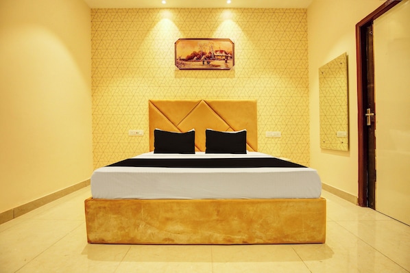 Quarto de hotel com uma cama grande, cabeceira e um quadro na parede.
