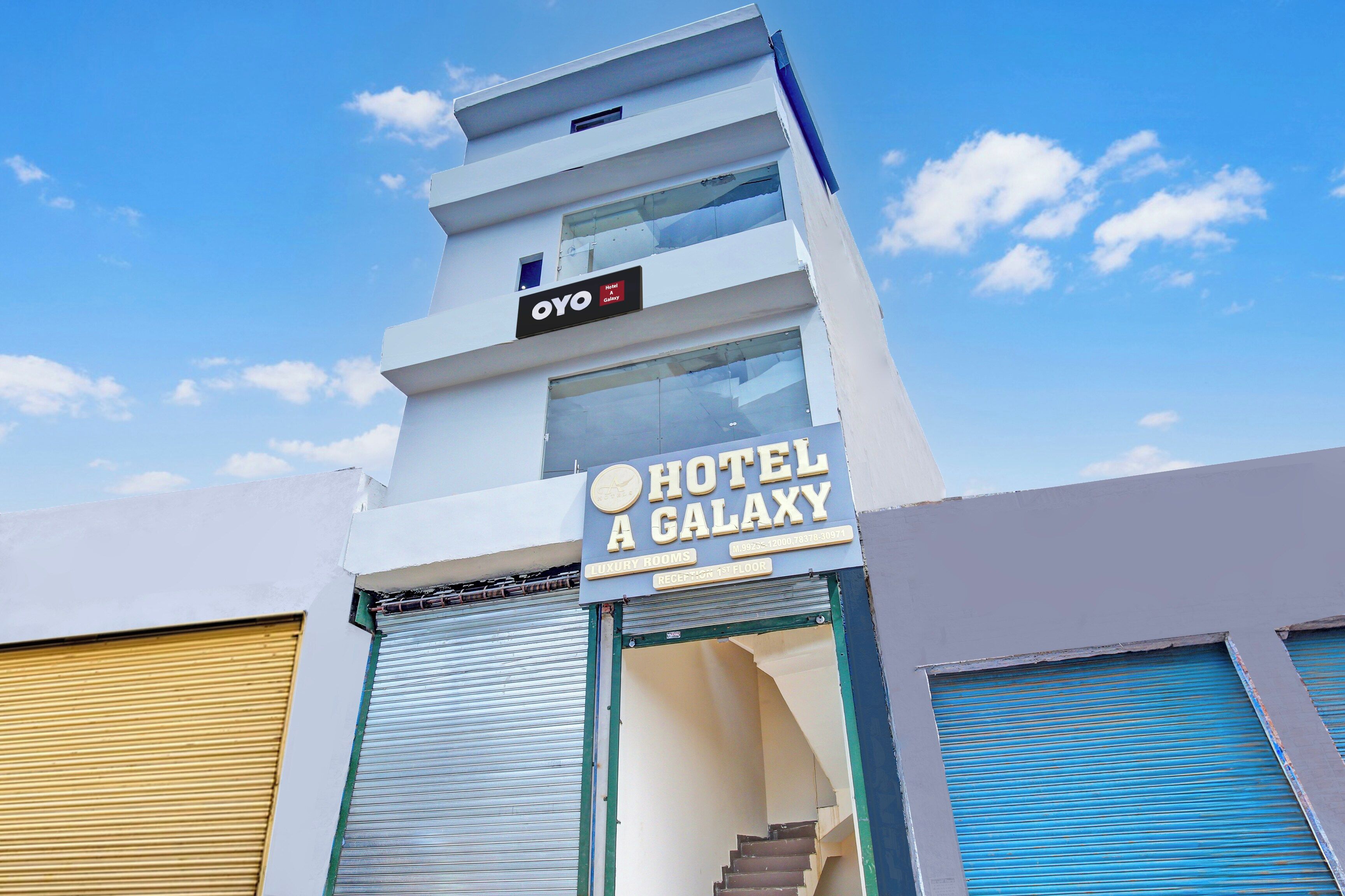 Une enseigne d’hôtel indiquant « HÔTEL A GALAXY » et « CHAMBRES DE LUXE », ce qui permet d’identifier le nom de l’hôtel et le type de chambres qu’il propose.