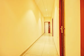 Um corredor com piso ladrilhado e uma porta à direita.