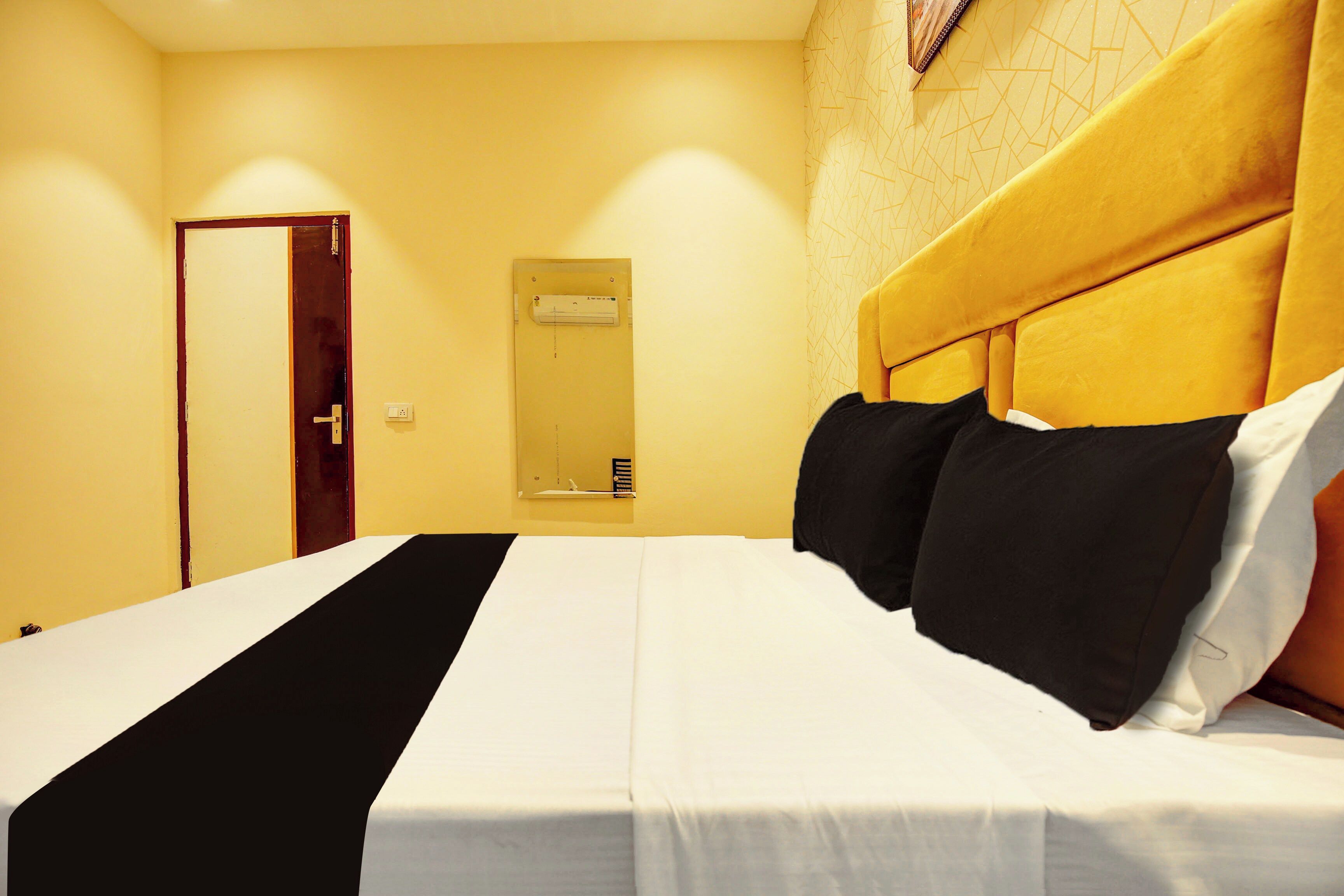 A hotel room with a bed, a door, and a wall-mounted air conditioning unit.