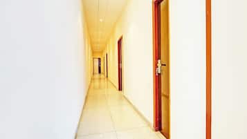 Un pasillo largo y estrecho con puertas a un lado y piso de baldosas.