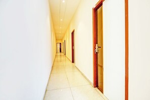 Un pasillo largo y estrecho con puertas a un lado y piso de baldosas.