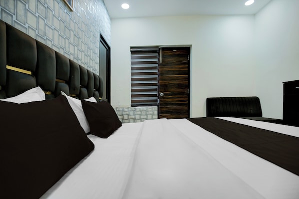 A hotel room with a large bed, a headboard, a wardrobe, and a door with a window. - Hotel O Crystal (Ludhiana)