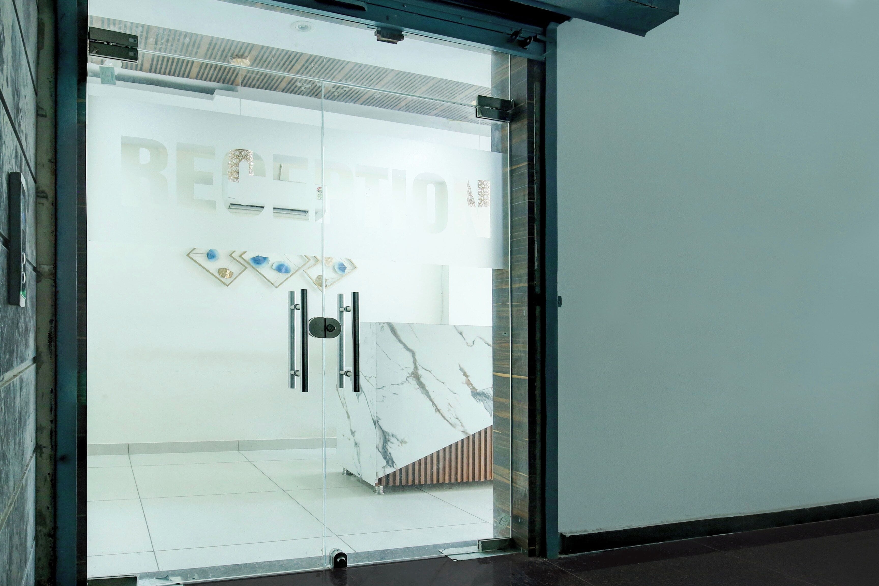 Un espace d’accueil doté d’une porte en verre, d’un mur en marbre et d’une enseigne indiquant « RÉCEPTION ».
