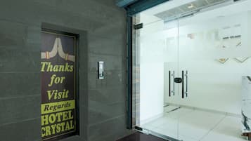 L’entrée d’un hôtel, avec une porte en verre, une enseigne remerciant les visiteurs et un aménagement intérieur moderne.