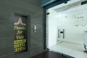 A hotel entrance with a glass door, a sign thanking visitors, and a modern interior design. - Hotel O Crystal (Ludhiana)
