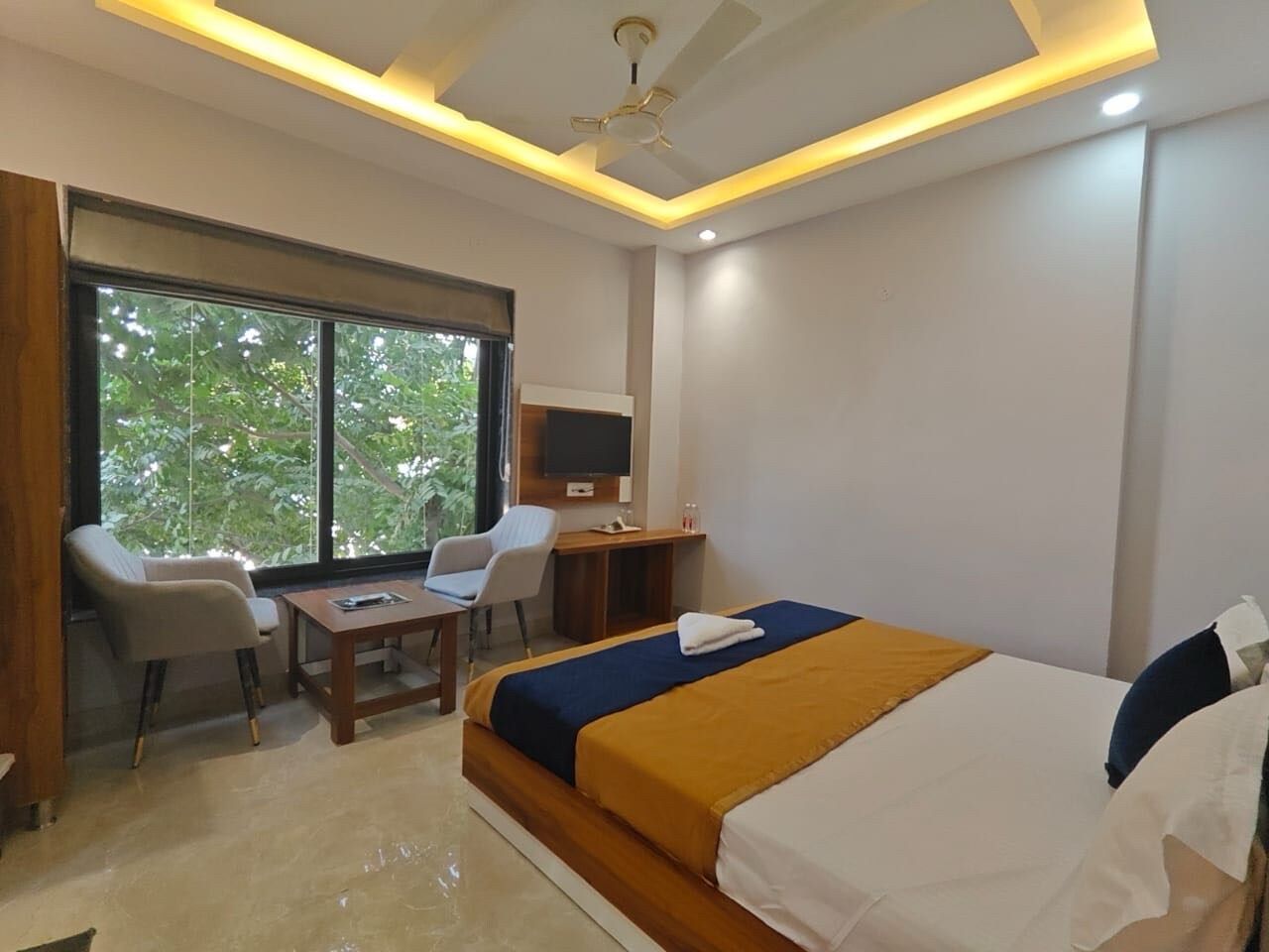 A hotel room with a bed, a desk, a chair, and a television.