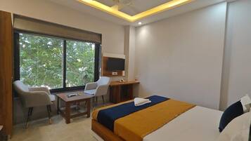 A hotel room with a bed, a desk, a chair, and a television.