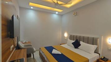 A modern hotel room with a bed, bedside table, and a flat-screen TV mounted on the wall.