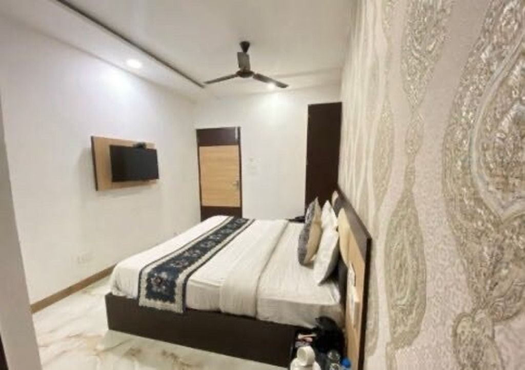 A bedroom with a bed, a ceiling fan, a flat-screen TV, and a patterned wall.