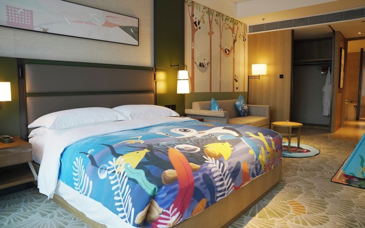 A hotel room with a bed, a sofa, a small table, and a shower area.