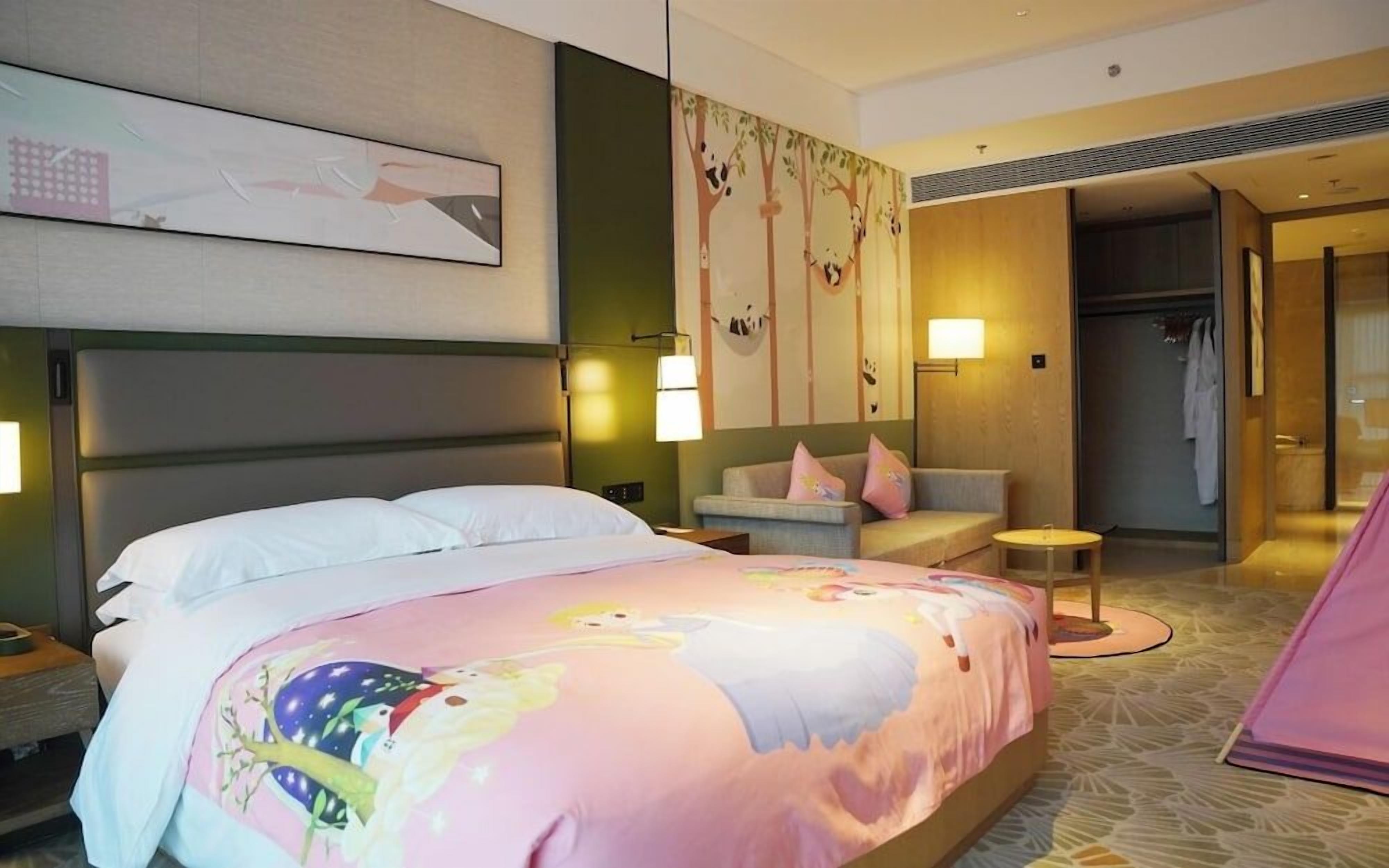 A hotel room with a large bed, a sofa, a small table, and a wardrobe.