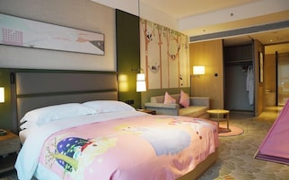 A hotel room with a large bed, a sofa, a small table, and a wardrobe.