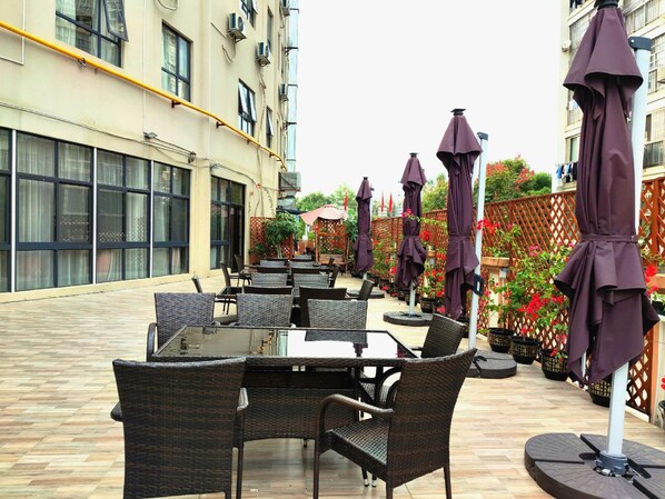 An outdoor seating area with tables and chairs, surrounded by umbrellas and potted plants. - Echarm Hotel Liuzhou Liudong Wuling Liuqi Branch (Liuzhou)
