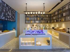 A modern interior with a central display area, shelves with various items, and a blue-tiled wall with a menu. - Echarm Hotel Liuzhou Liudong Wuling Liuqi Branch (Liuzhou)