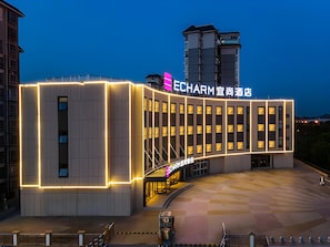 A modern hotel with a prominent sign, a covered entrance, and a parking area. - Echarm Hotel Liuzhou Liudong Wuling Liuqi Branch (Liuzhou)