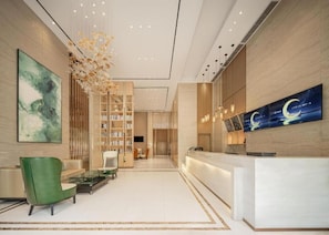 A modern hotel lobby with a reception desk, seating area, and a large wall-mounted artwork. - City Comfort Inn (Hechi)