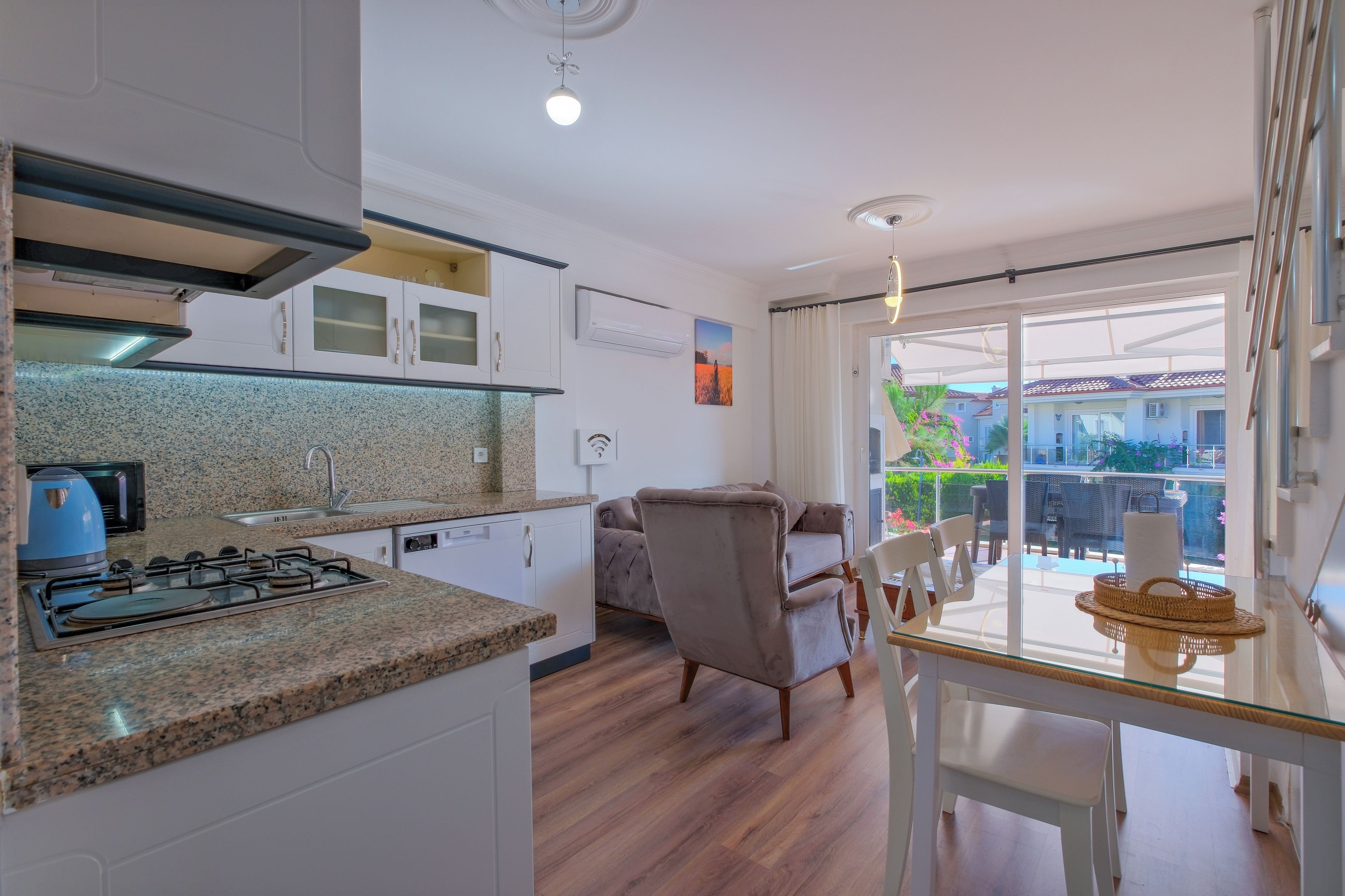 A modern kitchen with granite countertops, a gas stove, and white cabinetry.