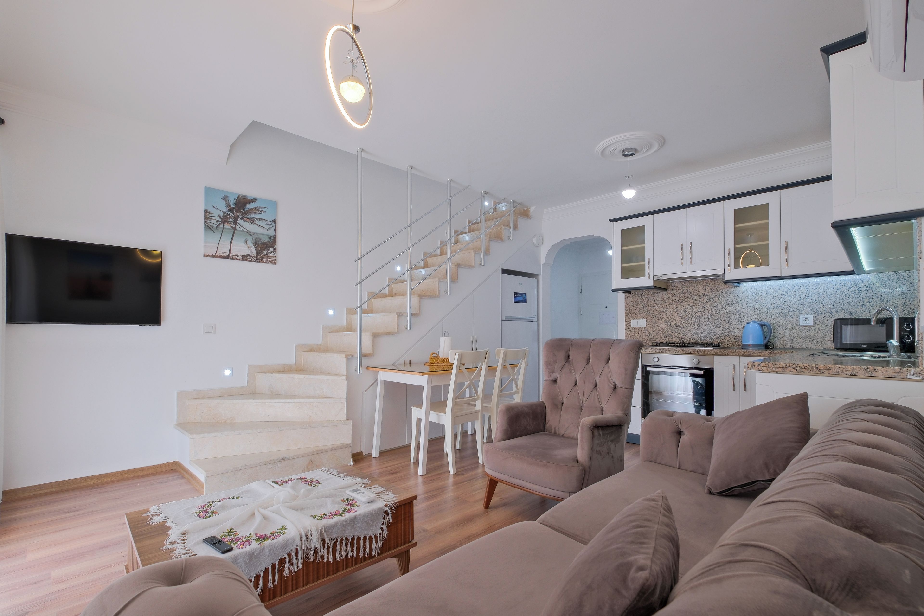 Una sala de estar moderna con sofá, una mesa de centro y una escalera que lleva a un comedor.
