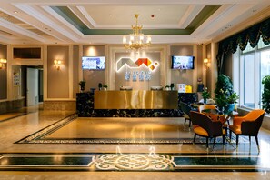 Ein Hotel-Rezeptionsbereich mit modernem Design, inklusive einer Rezeption, einer Sitzecke und dekorativer Beleuchtung.