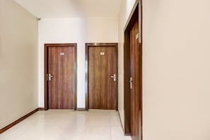 A hallway with two wooden doors, each marked with a number. - Hotel O City Inn (Amritsar)