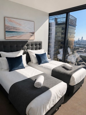 A hotel room with two beds, a large window with a city view, a grey headboard, and a painting on the wall. - Luxury 2BR | Ocean Views | Level 50 Broadbeach (Broadbeach)