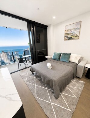 A modern bedroom with a large bed, a view of the city, and a balcony. - Luxury 2BR | Ocean Views | Level 50 Broadbeach (Broadbeach)