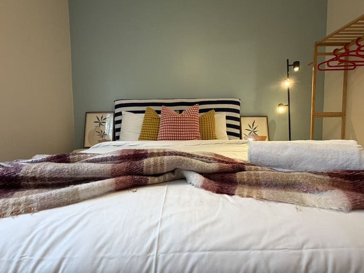 Un lit avec un oreiller à rayures, une couverture et une lampe de chevet.
