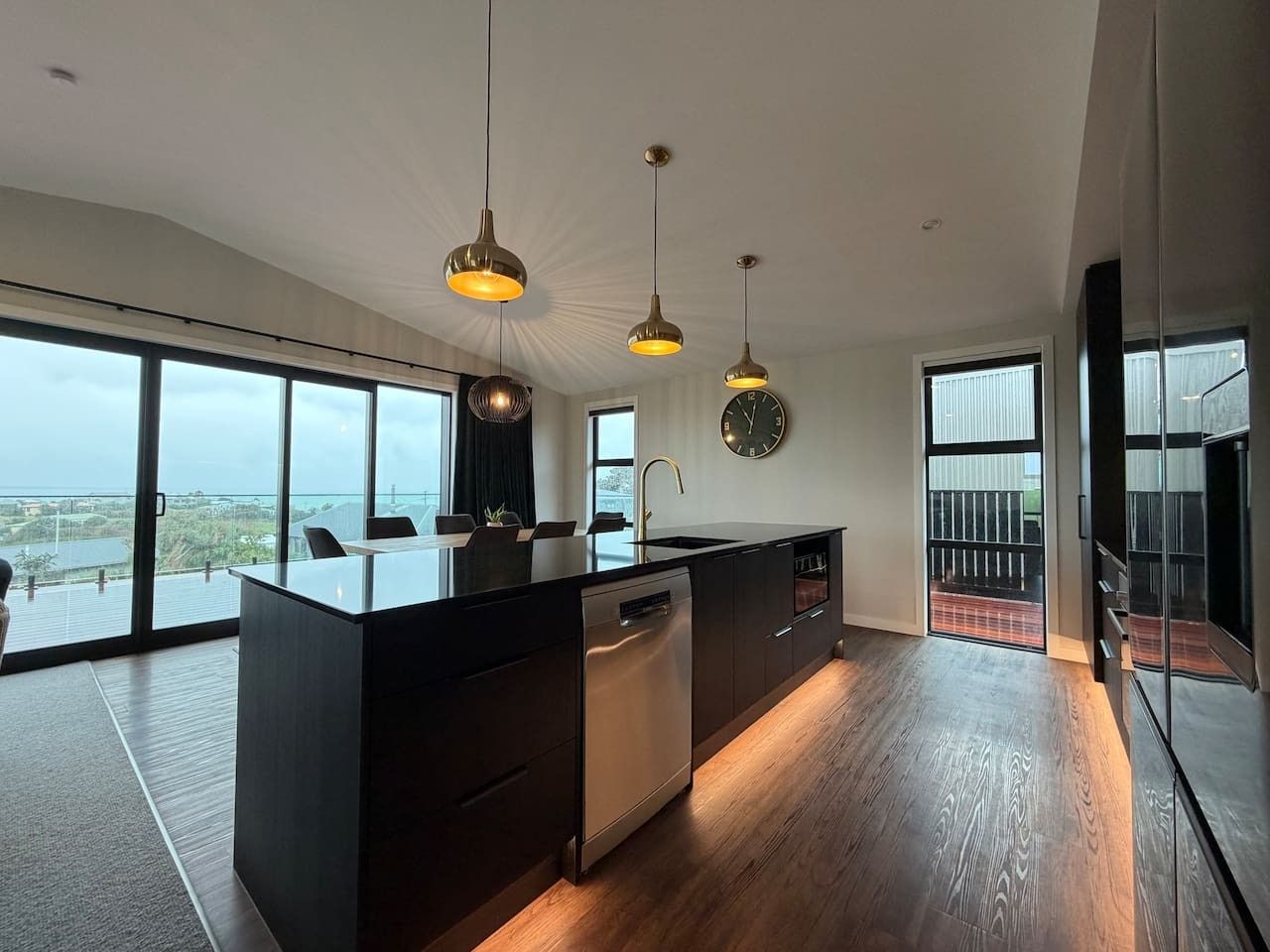 A modern kitchen with a central island, pendant lighting, and a view of the outdoors.