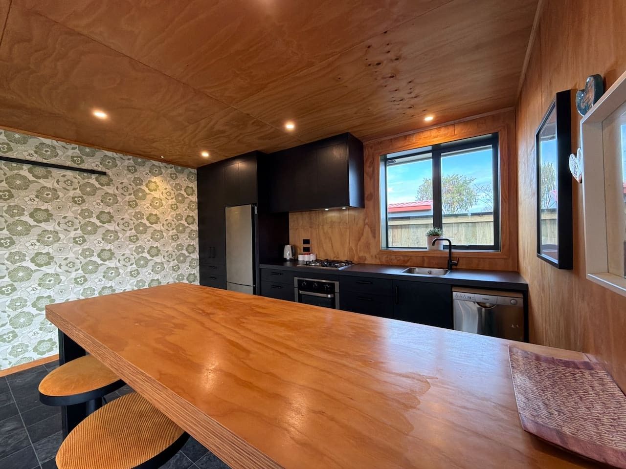 A modern kitchen with a wooden countertop, built-in appliances, and a window providing natural light.