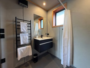 Ein modernes Badezimmer mit einem schwarzen Handtuchhalter, einem Spiegel, einem Waschbecken und einer Duschvorhang.