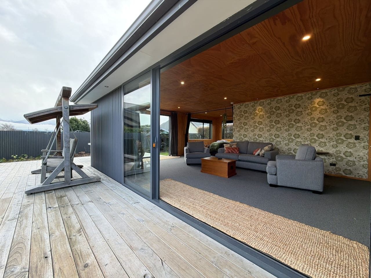 Un salon moderne avec un ensemble de canapés, une table basse et une terrasse en bois.