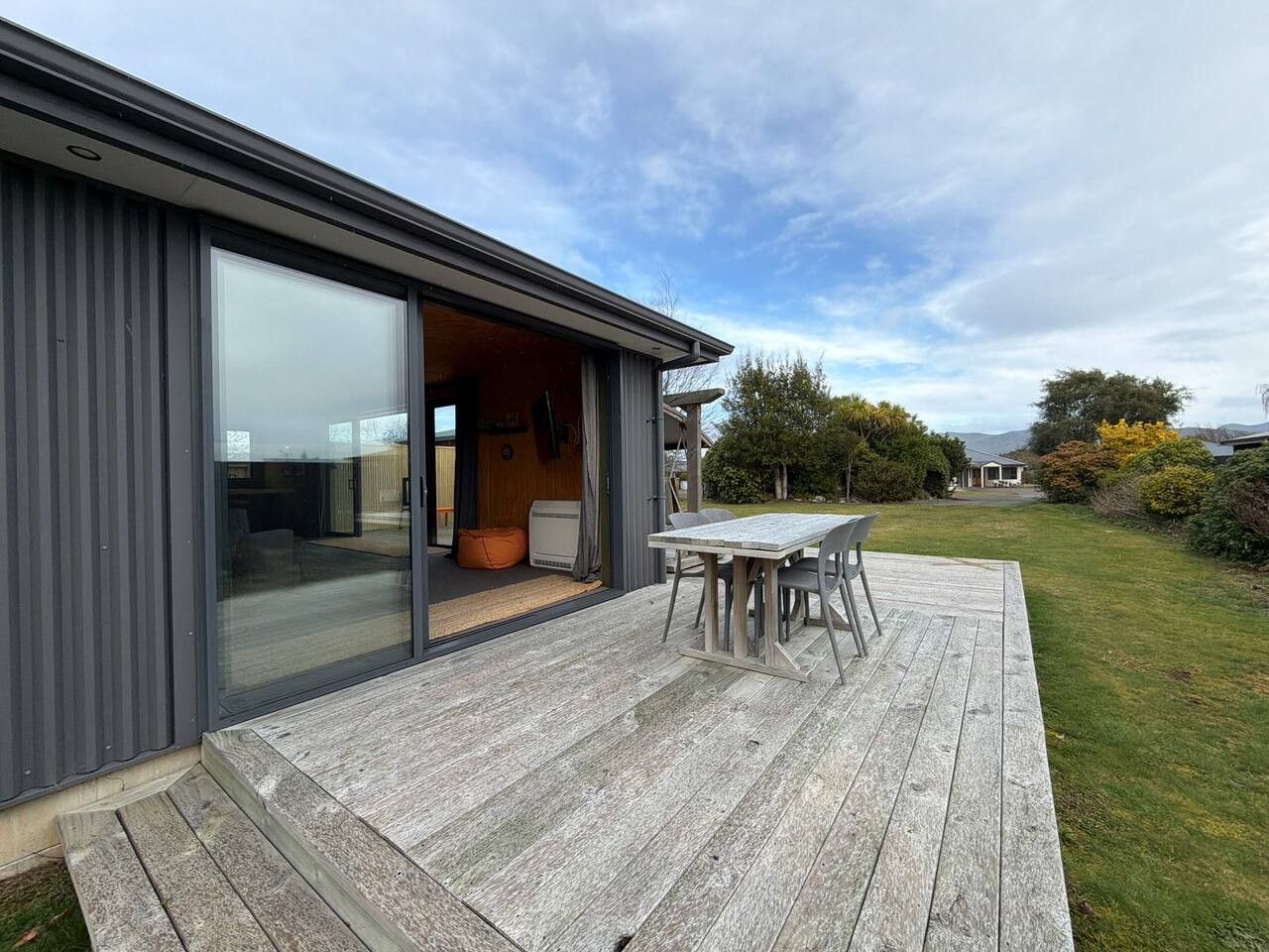 Une maison moderne dotée d’une terrasse, d’une porte-fenêtre coulissante donnant sur l’intérieur et offrant une vue sur le paysage environnant.