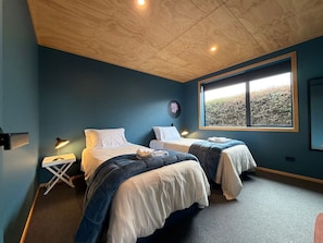 Ein Schlafzimmer mit zwei Betten, einem Fenster mit Blick und einer Decke mit Einbaustrahlern.