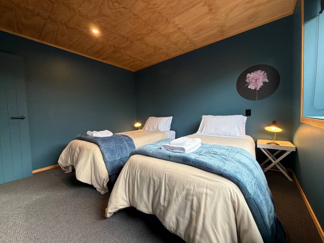Une chambre avec deux lits, un plafond en bois et une décoration florale fixée au mur.