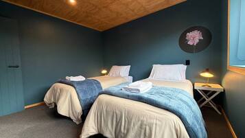 Une chambre avec deux lits, un plafond en bois et une décoration florale fixée au mur.