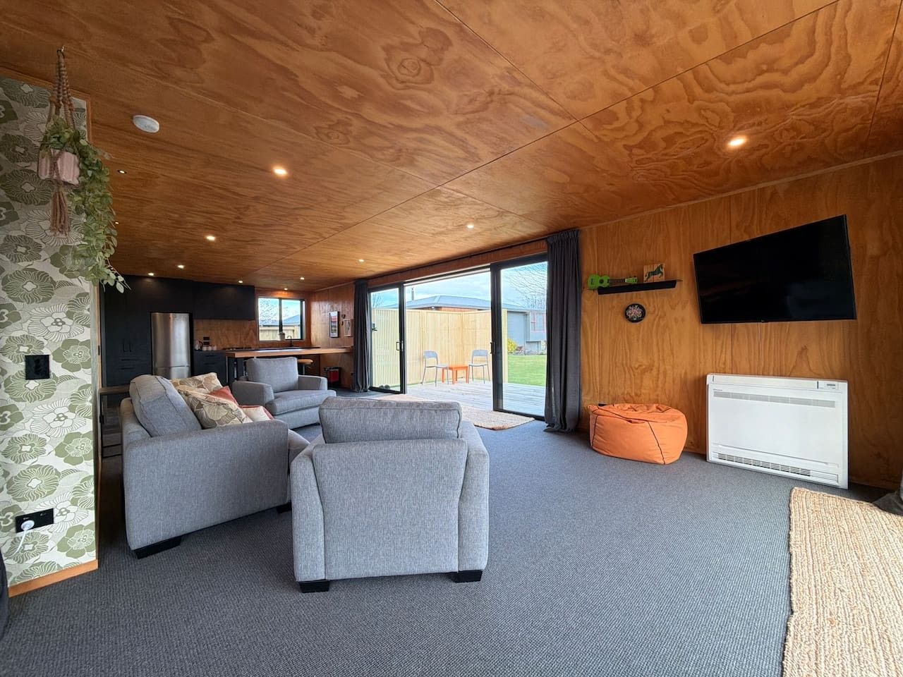 Un salon moderne avec des canapés gris, un téléviseur à écran plat et un plafond en bois.