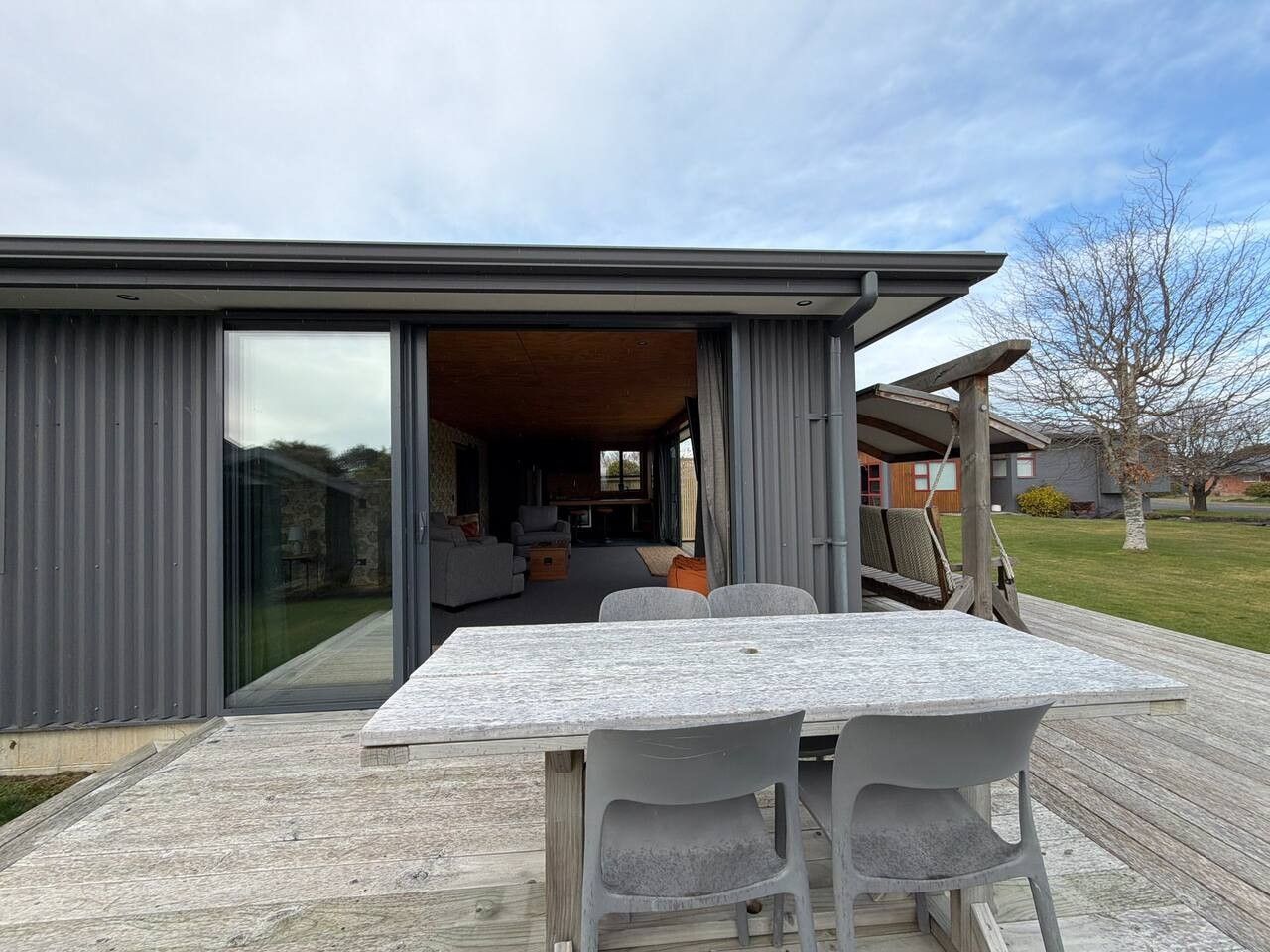Une maison moderne dotée d’un patio comprenant une table et des chaises.