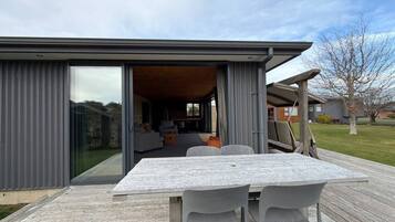 Une maison moderne dotée d’un patio comprenant une table et des chaises.