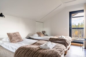 A hotel room with two beds, a large window, and a view of trees. - Levi North Apartment D11 by Aavalevi (Levi)