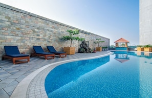 Piscina con sillones de descanso y pared de piedra.