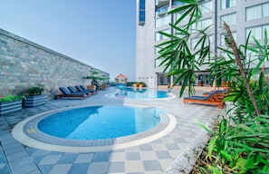 Una piscina con sillones de descanso y un muro de piedra.