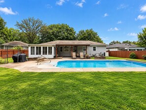 A residential backyard with a swimming pool, patio furniture, and a covered outdoor seating area. - Overland Park Retreat with Pool & Shuffleboard! (Overland Park)