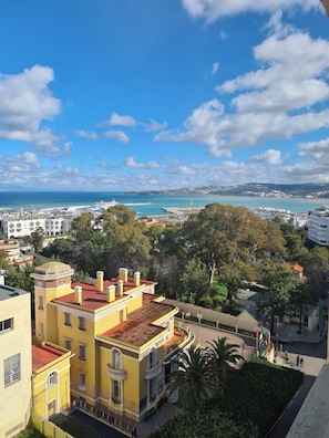 A coastal cityscape with a prominent yellow building, a marina with boats, and a clear blue sky. - Charming Tangier Apartment Central, Iconic, and Comfortable (Tanger)