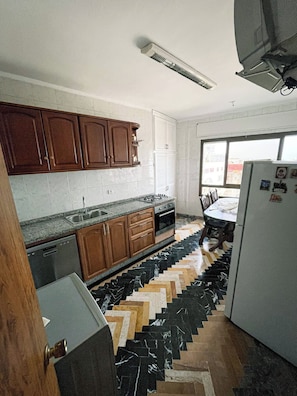 A kitchen with wooden cabinets, a stove, and a refrigerator. - Charming Tangier Apartment Central, Iconic, and Comfortable (Tanger)