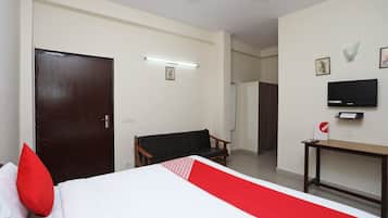 Una habitación de hotel con cama, escritorio, silla, televisor y puerta.